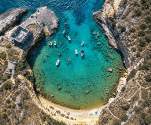 Εναέρια λήψη του όρμου του Μέζαπου στη Μάνη με τιρκουάζ νερά, βάρκες και βραχώδες τοπίο